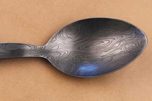 Bowl-side view of stainless random damascus chef's spoon.